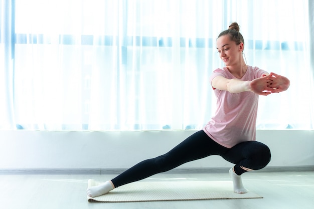 Junge Frau machen Dehnungsmuskel- und Fitnessübungen auf Yogamatte zu Hause. Abnehmen und fit bleiben. Gesunder Sportlebensstil