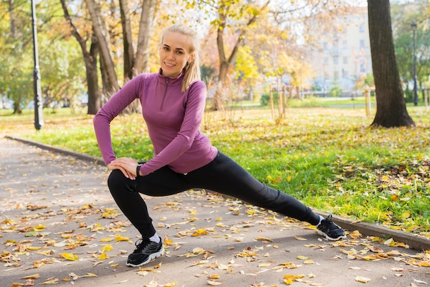 Junge Frau macht Dehnübungen im Park Sport draußen im Herbst