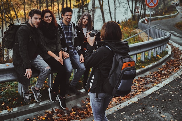 Junge Frau macht ein Foto ihrer Freunde mit Digitalkamera im Herbstwald.