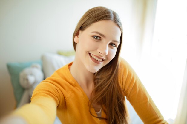 Junge Frau macht ein Selfie, während sie zu Hause Spaß hat