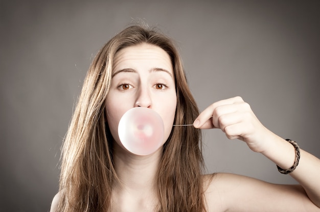 junge Frau macht eine Blase aus einem Kaugummi
