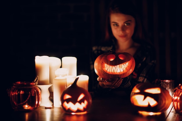 Junge Frau macht Halloween-Kürbis Jackolantern Weibliche Hände schneiden Kürbisse mit Messer