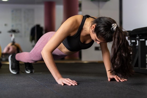 Foto junge frau macht liegestütze im fitnessstudio