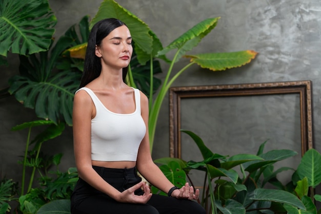 Foto junge frau macht morgendliche yoga und meditation im natürlichen garten mit pflanzenblättern, genießt die einsamkeit und praktiziert meditative posen achtsamkeitsaktivität und gesunder lebensstil blithe