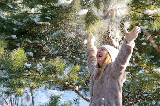 Foto junge frau macht spaß im winterpark an einem sonnigen tag in der nähe von schneebedeckten tannen und kiefern