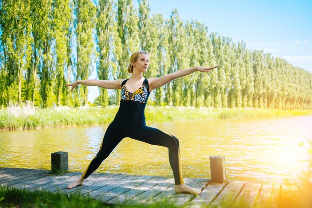 Junge Frau macht Yoga-Asanen im Park, Mädchen dehnt sich in der Yoga-Position, glücklich und gesund