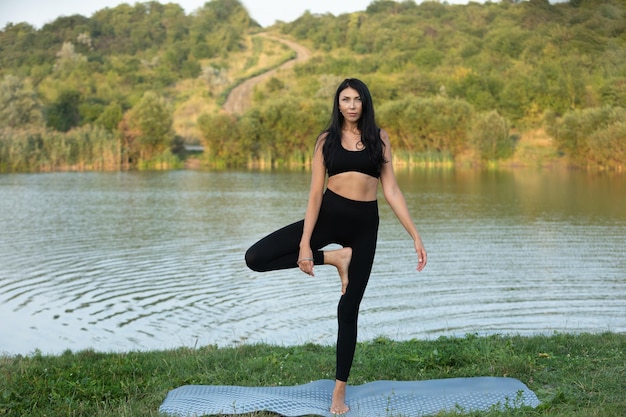 Junge Frau macht Yoga in der Nähe des Sees Entspannen Sie sich im Freien Sportmeditation Wellness Sommerfitness
