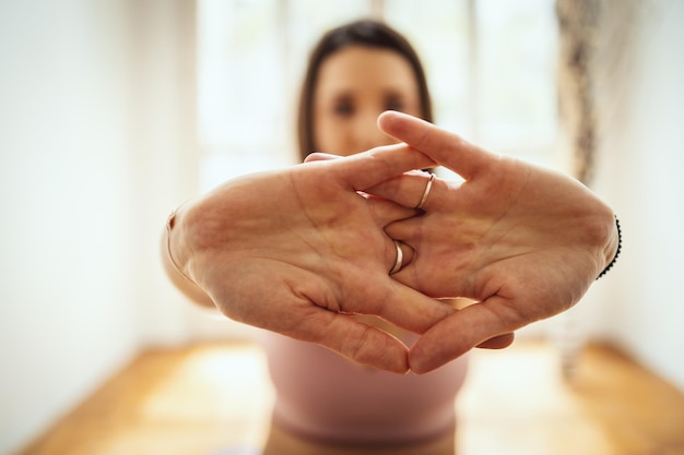 Junge Frau macht Yoga-Meditation im Wohnzimmer zu Hause. Sie meditiert auf der Bodenmatte im Morgensonnenschein.