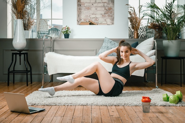 Junge Frau macht zu Hause Sport und trainiert online