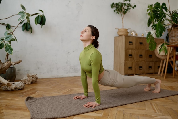 Junge Frau macht zu Hause Yoga-Dehnübungen. Wohlbefinden und gesundes Sport-Lifestyle-Konzept