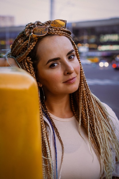 junge Frau mit Afro-Zizi-Zöpfen und hellem Make-up in einer Großstadt, Porträt. zizi zöpfe frisuren.