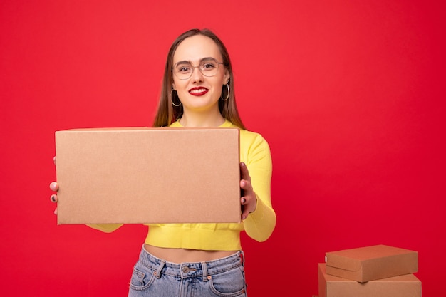 Junge Frau mit beweglichen Kisten auf rotem Hintergrund