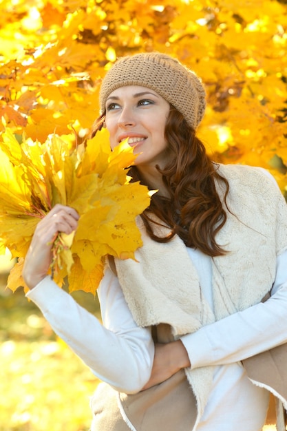 Junge Frau mit Blättern, die im Herbstpark aufwerfen