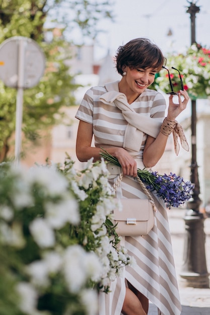 Junge Frau mit Blumen in der Stadt spazieren