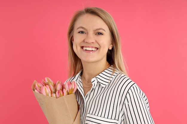 Junge Frau mit Blumenstrauß auf rosa Hintergrund