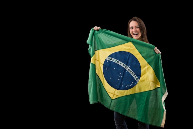 Junge Frau mit brasilianischer Flagge auf einer schwarzen Wand.