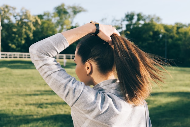 Junge Frau mit braunen Haaren in einem sonnigen Park