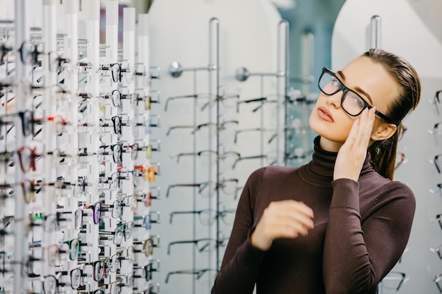 Junge Frau mit Brille im Optikgeschäft Schönes Mädchen mit Brille im Optikergeschäft Augenheilkunde