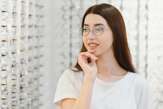 Junge Frau mit Brille im Optikgeschäft Schönes Mädchen mit Brille im Optikergeschäft