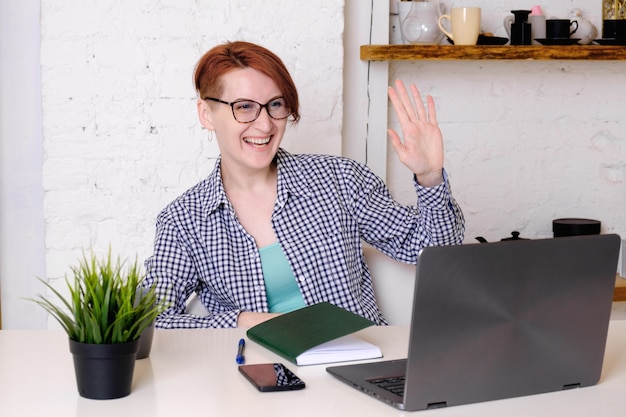Junge Frau mit Brille sitzt vor Laptop-Bildschirm im Bürokonzept des Online-Lernens