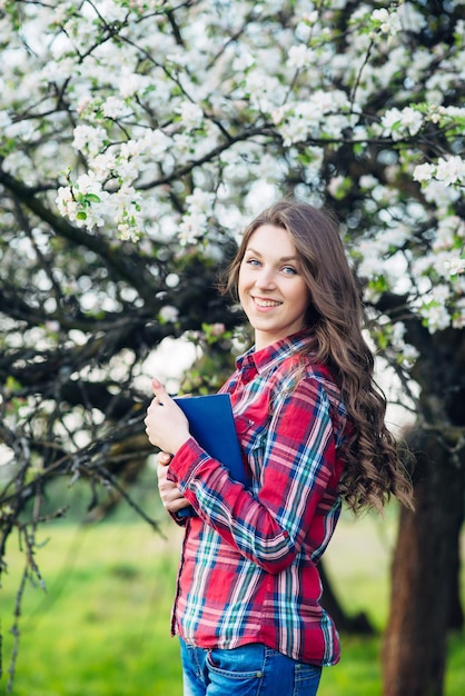 Junge Frau mit Buch in einem blühenden Garten