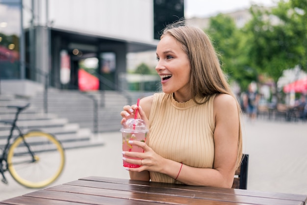 Junge Frau mit Cocktail im Straßencafé