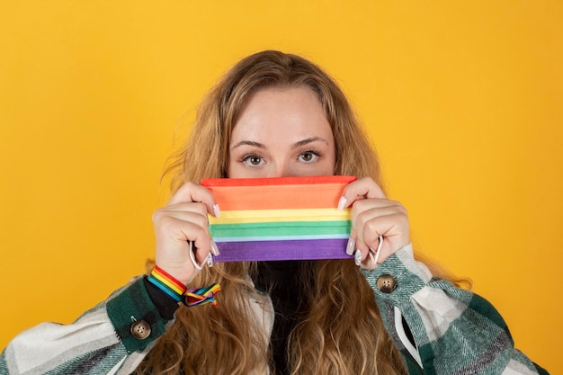 Junge Frau mit der Flagge des schwulen Stolzes, die Regenbogenfahnensymbol von LGBT hält