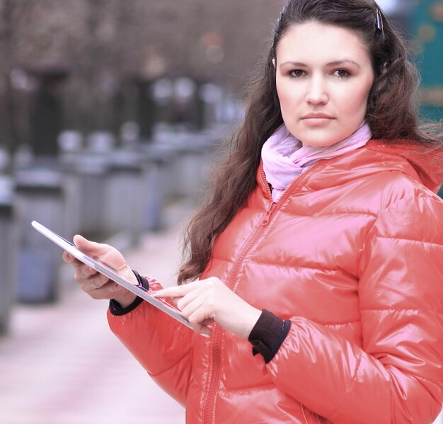 Junge Frau mit digitalem Tablet auf verschwommenem Stadthintergrund