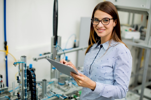 Junge Frau mit digitaler Tablette in der Elektronikwerkstatt