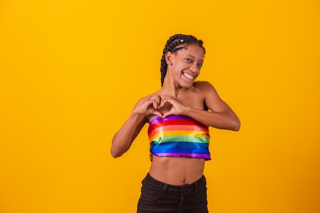 Junge Frau mit Dreadlocks und lesbischen Zöpfen behaaren. Sie selbst. Schöne und glückliche junge Afrofrau mit dem Symbol der Menschenrechte LGBT, Gleichberechtigung, LGBT. Lesben machen ein Herz mit der Hand