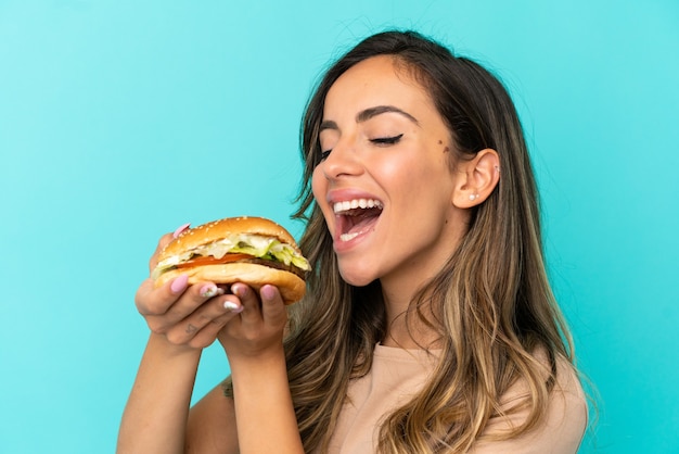 Junge Frau mit einem Burger über isoliertem Hintergrund