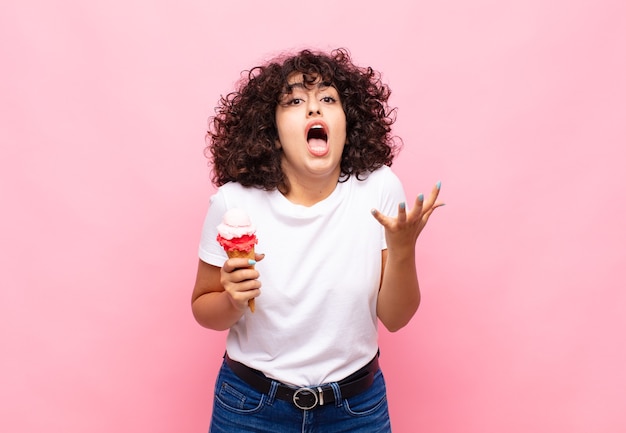 Junge Frau mit einem Eis, das verzweifelt und frustriert, gestresst, unglücklich und genervt aussieht, schreit und schreit