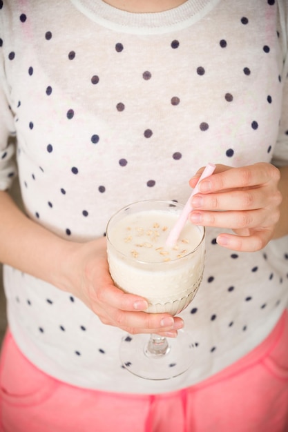 Junge Frau mit einem großen Glas gesundem Smoothie, serviert mit Strohhalm und Hafer