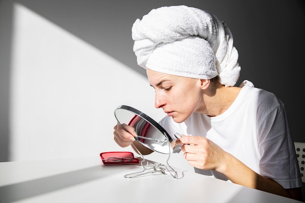 Junge Frau mit einem Handtuch auf dem Kopf, die morgens Make-up aufträgt