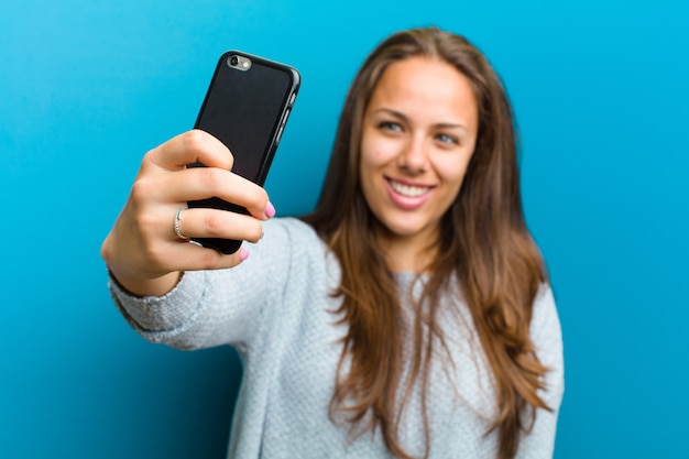 Junge Frau mit einem Handy auf Blau