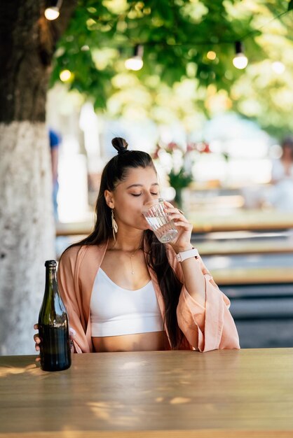 Junge Frau mit einem kalten Getränk, die in einem Café auf der Straße sitzt
