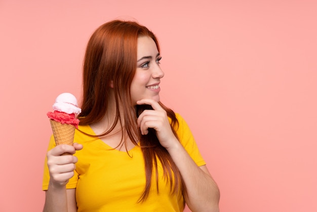 Junge Frau mit einem Kornetteis, das eine Idee denkt und Seite schaut