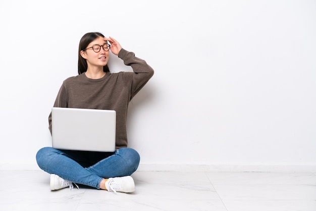 Junge Frau mit einem Laptop auf dem Boden sitzend hat etwas erkannt und beabsichtigt die Lösung