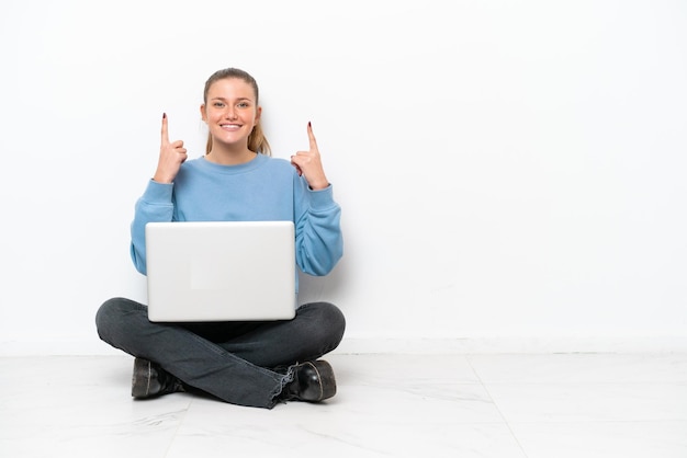 Junge Frau mit einem Laptop, der auf dem Boden sitzt und eine große Idee aufzeigt