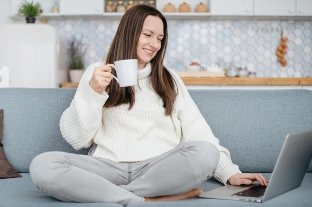 Junge Frau mit einem Laptop in einer gemütlichen Wohnung