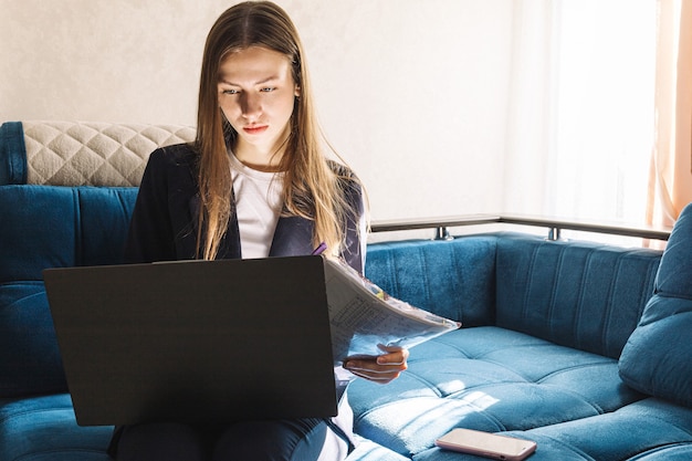 Junge Frau mit einem Notebook studiert oder arbeitet zu Hause und arbeitet mit einem Marketingbericht