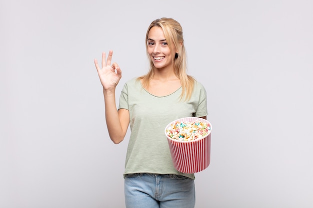 Junge Frau mit einem Popcorn-Eimer, die sich glücklich fühlt