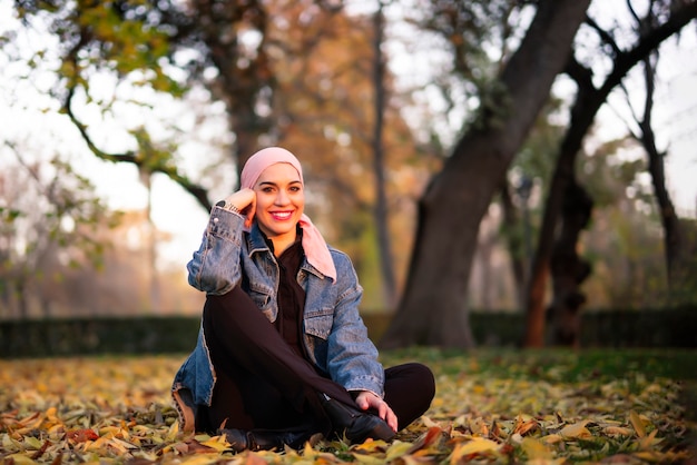 Junge Frau mit einem rosa Schal auf ihrem Kopf im Park