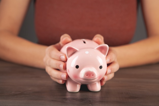 Junge Frau mit einem Sparschwein am Tisch