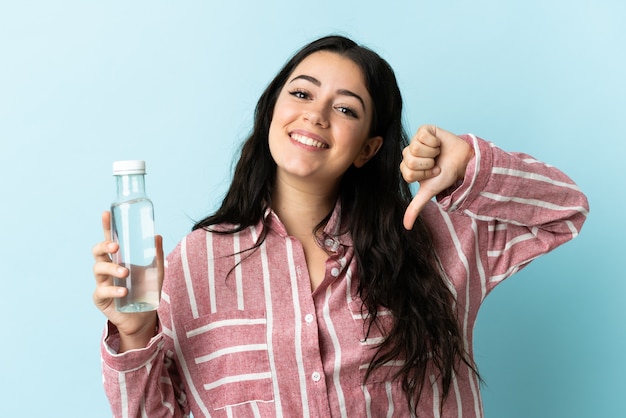 Junge Frau mit einem Wasser isoliert auf blauer Wand stolz und selbstzufrieden