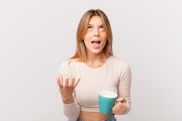 Junge Frau mit einer Kaffeetasse, die verzweifelt, frustriert und gestresst aussieht