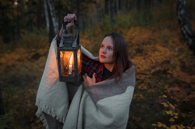 Junge Frau mit einer Petroleumlampe im Wald