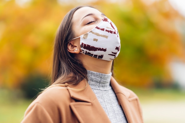 Junge Frau mit einer Schutzmaske im Herbstpark