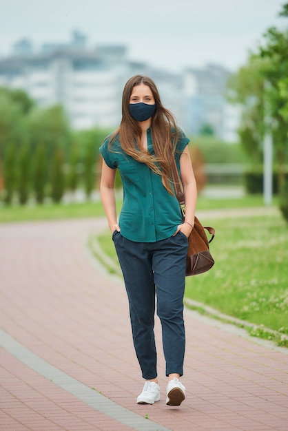 Junge Frau mit einer schwarzen Gesichtsmaske im Park