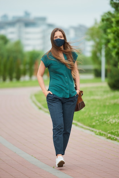 Junge Frau mit einer schwarzen Gesichtsmaske im Park